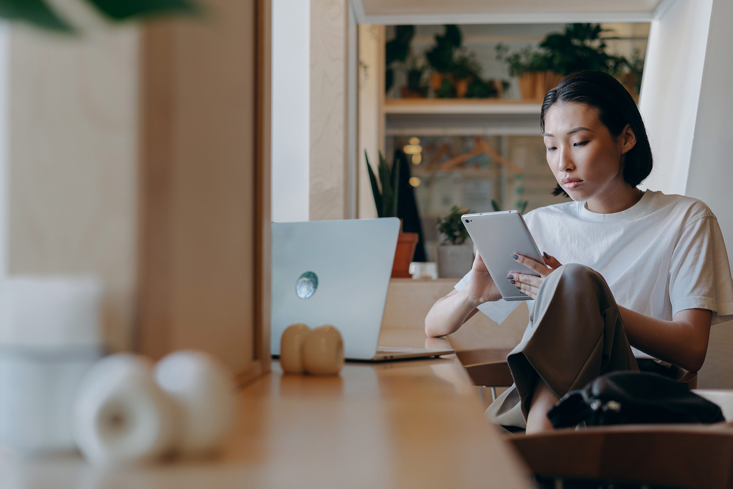 Frau zu Hause mit Tablet und Laptop